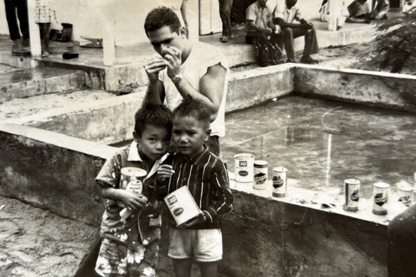 Amercian GI’s with Vietnamese children by swimming pool they build during the Vietnam War